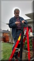electrician standing on an orange step ladder working on a light post
